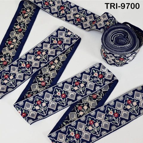 several rolls of blue and white embroidered fabric, featuring intricate floral and geometric patterns. The fabric appears to be a decorative textile, possibly used for clothing or home decor.