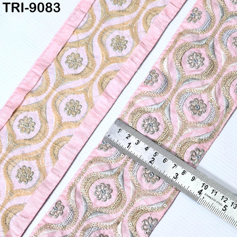 a close-up view of a decorative fabric with a repeating pattern of pink and gold floral designs. A ruler is placed on the fabric, indicating its size or dimensions.