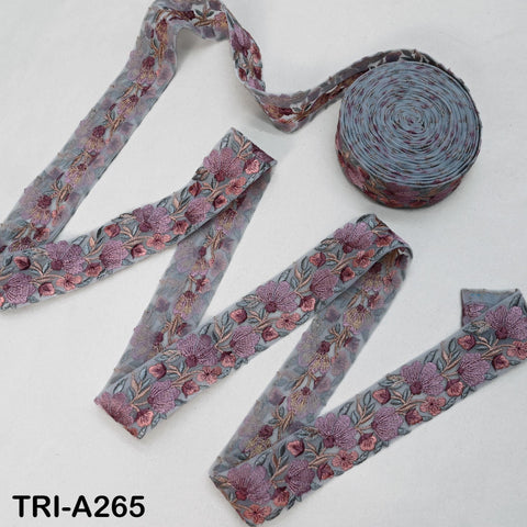 a spool of grey fabric with a floral pattern and a piece of the fabric lying on a white surface.