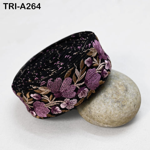 a black and purple floral embroidered fabric, possibly a headband or accessory, resting on a gray rock.