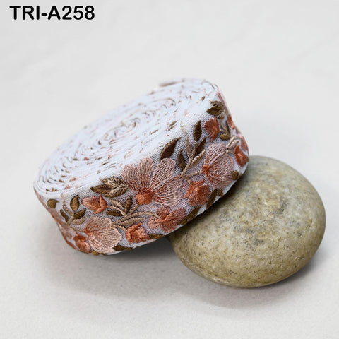 a decorative fabric with a floral pattern, placed on a white surface next to a round, gray stone.