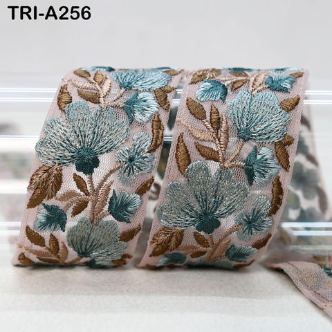 a decorative fabric with a floral pattern in shades of blue and brown. The fabric appears to be a piece of lace or a similar type of textile, with intricate embroidered designs.