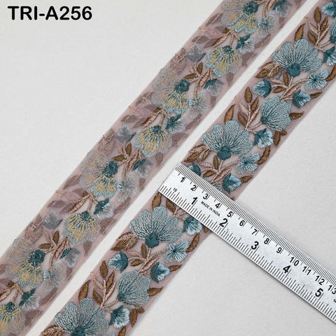 two spools of pink and blue floral embroidered fabric, with a ruler placed between them to measure the width of the fabric.