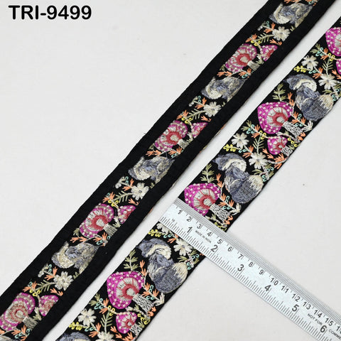 a decorative fabric with a floral pattern, featuring a black border and a ruler placed on top of it.