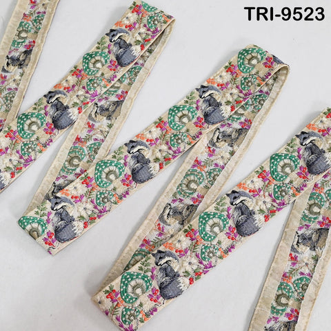several colorful, patterned fabric pieces with a repeating design of animals, such as raccoons or badgers, and flowers or leaves. The fabric appears to be embroidered or printed with a floral or animal motif.