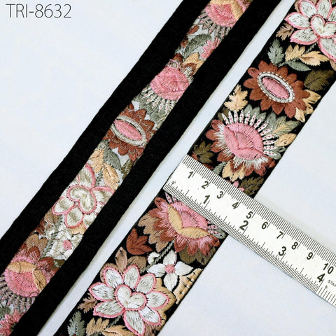 a close-up view of a decorative fabric with a floral pattern, featuring a black border. A ruler is placed on the fabric, indicating its size.
