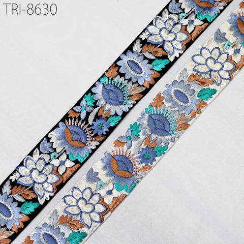 two spools of embroidered fabric with floral designs in shades of blue, green, and brown.