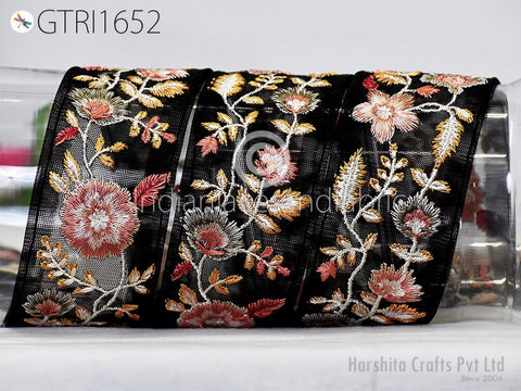 a decorative black fabric with a floral pattern, including pink and orange flowers, as well as leaves and stems. The fabric appears to be a decorative textile or ribbon, possibly used for embellishment or fashion purposes.