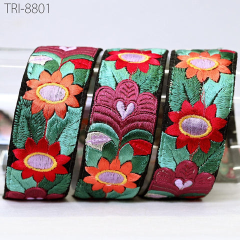 three colorful, intricately embroidered flower-shaped ribbons.