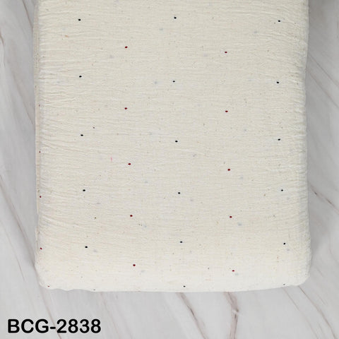 a white fabric with small red and black dots on it, placed on a marble surface.