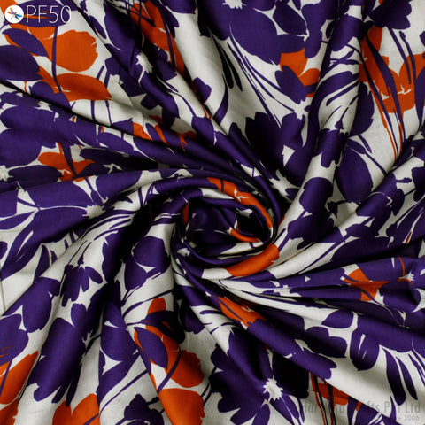 The image is a close-up view of a fabric with a floral pattern in shades of purple, orange, and white. The fabric appears to be made of silk and is displayed in a criss-cross pattern, creating a visually interesting and textured appearance.