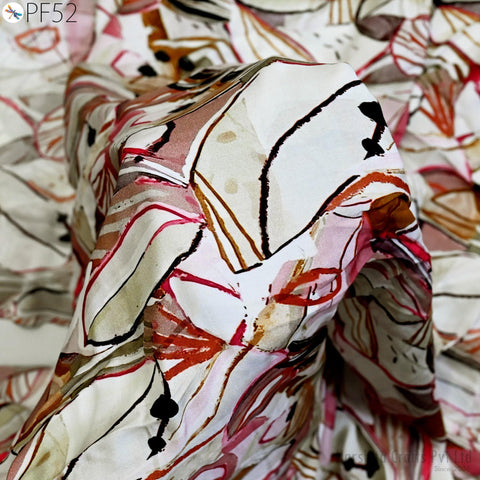 The image is a close-up of a fabric with a colorful, abstract pattern. The fabric appears to be made of a soft, white material with a mix of red, orange, and black colors. The pattern is intricate and visually striking, with various shapes and lines creating a dynamic and eye-catching design.