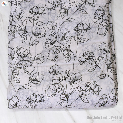 a close-up view of a fabric with a repeating floral pattern in black and white. The pattern consists of various flowers and leaves, creating a visually striking and intricate design. The fabric appears to be a piece of cloth or textile, possibly used for clothing or home decor.