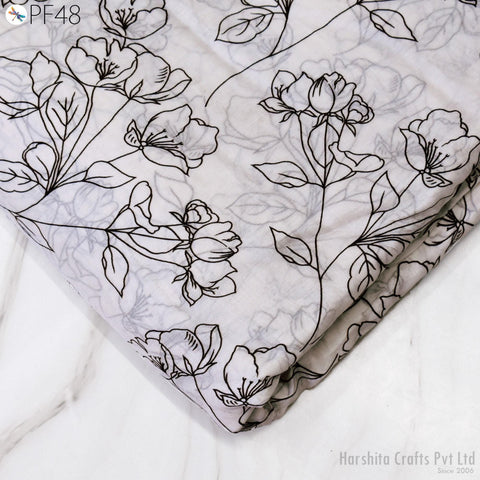 a close-up view of a fabric with a floral pattern, featuring black outlines of flowers and leaves. The fabric appears to be a light-colored material, possibly cotton or linen, with a subtle texture. The image does not contain any text or additional objects, and the focus is solely on the floral pattern on the fabric.