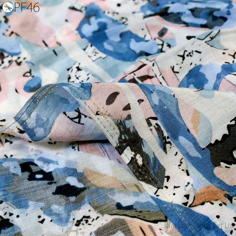 a close-up view of a fabric with a colorful, abstract pattern. The fabric appears to be a piece of clothing or textile, with a mix of blue, pink, and black colors and various shapes and designs.