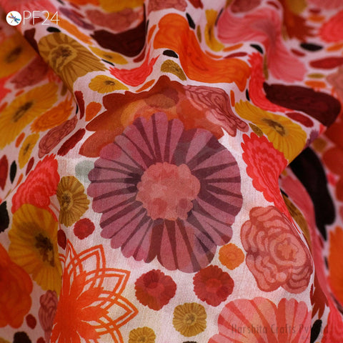 The image is a close-up of a fabric with a vibrant, colorful floral pattern. The fabric appears to be made of silk and features a variety of flowers in shades of orange, pink, and yellow. The pattern is intricate and detailed, showcasing the craftsmanship of the fabric.