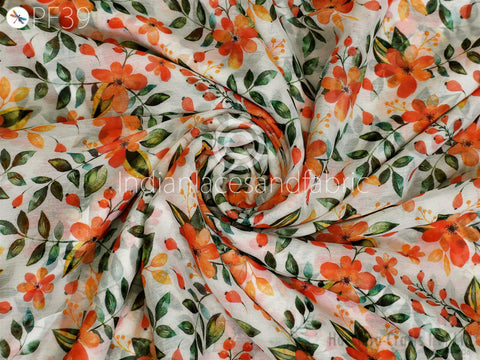 The image is a close-up view of a fabric with a floral pattern, featuring orange and green flowers and leaves.