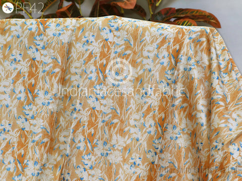 a fabric with a floral pattern in shades of yellow and white. The fabric appears to be folded or draped, with the pattern visible on the surface.
