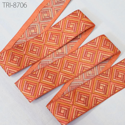 a collection of orange and red patterned fabric pieces, including a large piece with a diamond pattern and smaller pieces with a geometric pattern. The fabric appears to be made of a shiny material and is displayed against a white background.