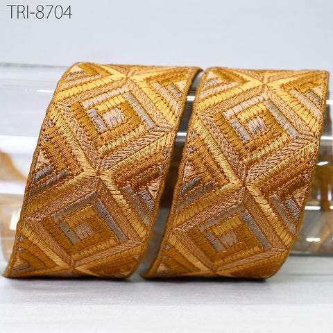 two gold-colored fabric pieces with a geometric pattern, placed on a white surface.