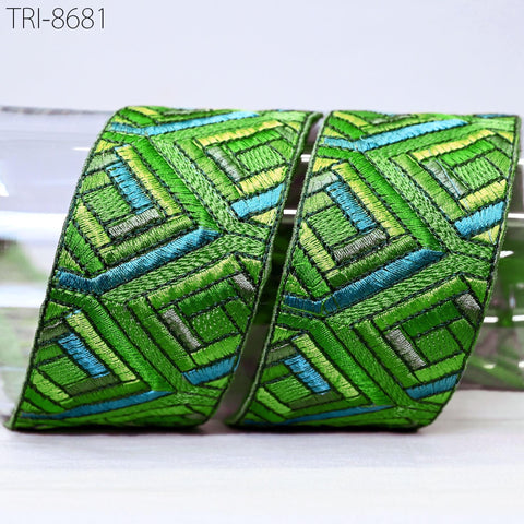 two pieces of green and blue embroidered fabric, with a geometric pattern of intersecting lines and shapes.