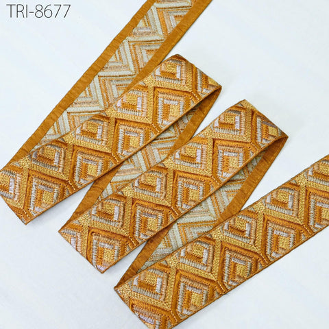 a collection of gold and white patterned fabric pieces, including a long piece of fabric with a repeating diamond pattern and a shorter piece with a similar diamond pattern. The fabric appears to be made of a shiny, metallic material.
