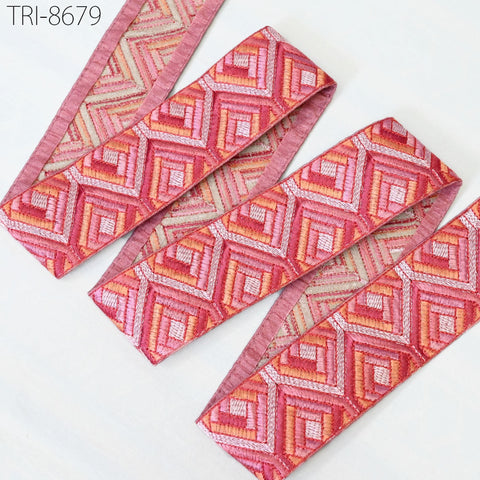 a collection of pink and orange patterned fabric pieces, including a pink and orange geometric patterned fabric and a pink and orange fabric with a diamond pattern.