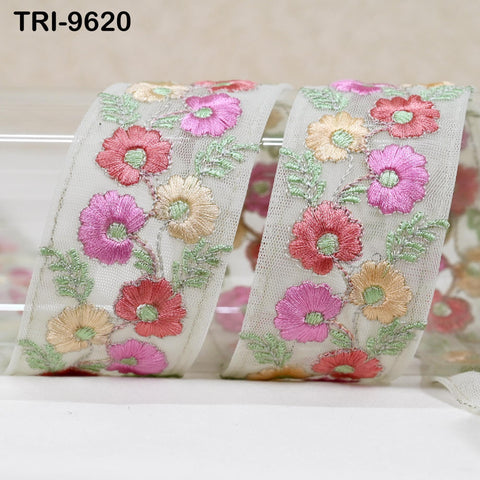 a decorative fabric with a floral pattern, including pink, yellow, and green flowers. The fabric appears to be a ribbon or a piece of lace, with the flowers intricately embroidered or sewn onto it.