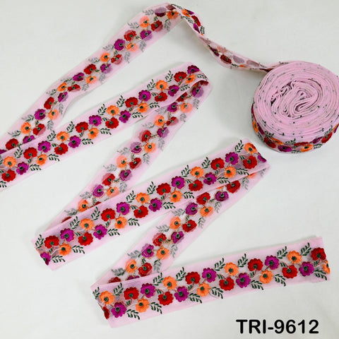 a pink floral embroidery ribbon and a spool of pink fabric with a floral pattern.