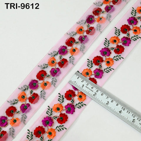 a pink fabric with a floral embroidered design, and a ruler is placed on top of it, indicating the size of the fabric.