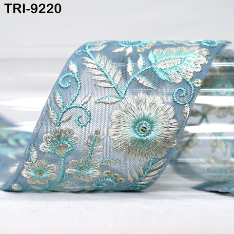 A close-up image of a decorative blue and white floral embroidered ribbon.