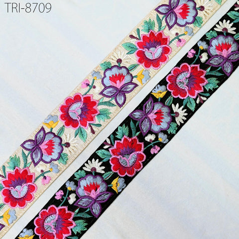two decorative fabric pieces with floral patterns. The left piece has a floral design with red, purple, and white flowers, while the right piece has a floral design with red, purple, and white flowers, as well as green leaves. The two pieces are placed side by side, creating a visually appealing contrast between the two floral patterns.