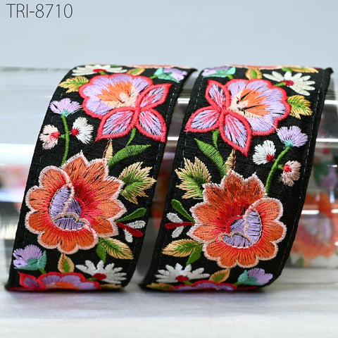two decorative fabric pieces with a floral pattern, including large orange and pink flowers, along with smaller flowers and leaves. The fabric appears to be black with a colorful, intricate embroidered design.