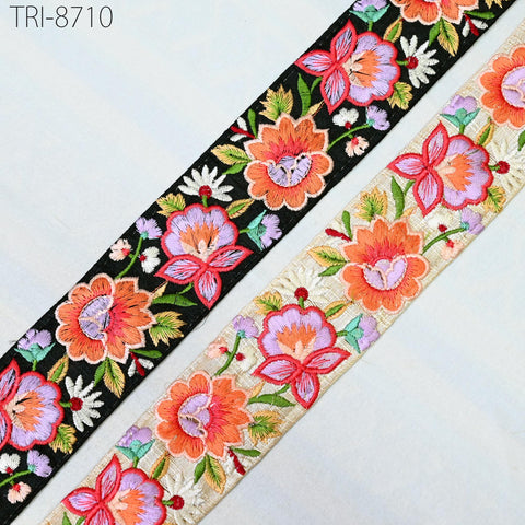 two spools of embroidered fabric with floral patterns. The spools are placed side by side, with the left one appearing to be black and the right one being white.