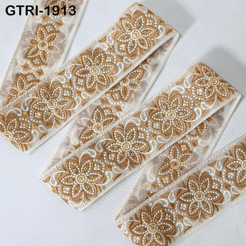 a close-up view of a decorative fabric with a floral pattern. The fabric appears to be made of a shiny, metallic material and has a repeating floral design. The fabric is arranged in a zigzag pattern, creating a visually appealing and intricate design.