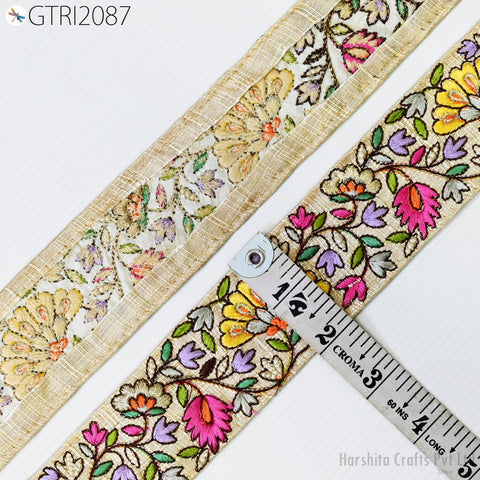 two pieces of fabric with a floral pattern, one with a gold border and the other with a beige border. A ruler is placed between the two pieces of fabric, indicating their size.