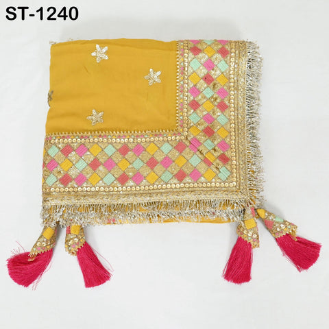 a decorative fabric with a yellow background and a border of colorful geometric patterns. The fabric has a fringe design and tassels on the edges.