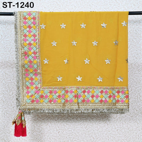 a yellow fabric with a decorative border and tassel hanging on a black rod.