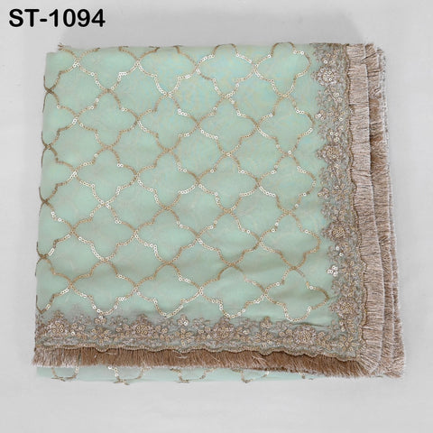a light green fabric with a gold and white sequin pattern, featuring a decorative border with fringe.