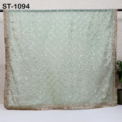 a large, light green fabric with a gold and white diamond pattern, hanging on a wall.