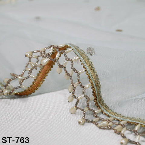 a delicate, ornate beaded fringe or lace trim on a white fabric, with a gold and white color scheme.
