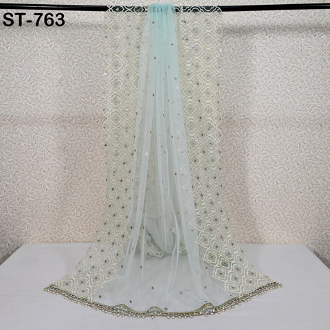 a light blue, sheer, and patterned fabric draped over a white surface, with a black railing visible in the background.