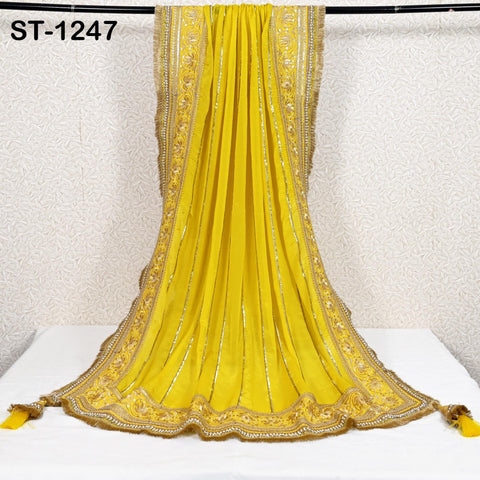 a long, yellow, and gold sari draped over a white surface.