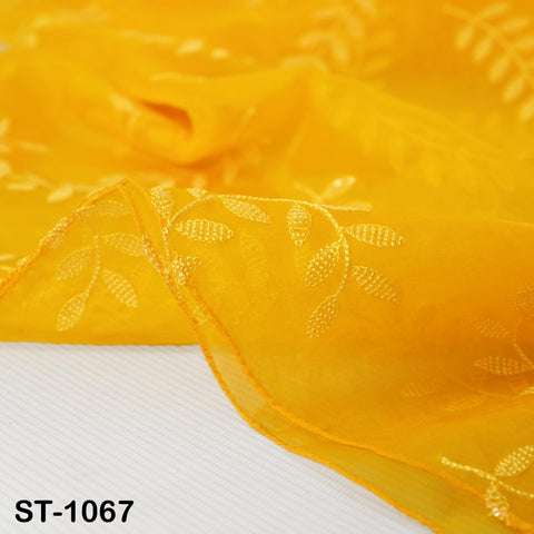 a close-up view of a yellow fabric with a floral pattern, featuring small white embroidered leaves.