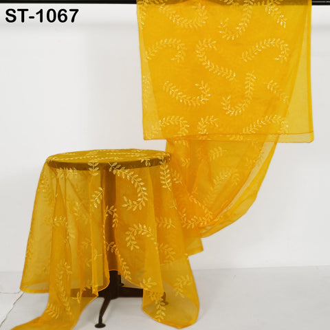 a yellow fabric with a leaf pattern, hanging on a stand.