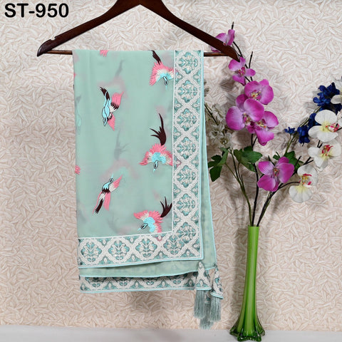 a light blue and green patterned fabric hanging on a wooden hanger, with a vase of pink and purple flowers placed next to it on a table.