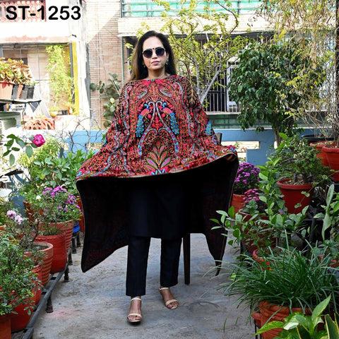 A woman wearing a colorful, patterned dress stands in a garden surrounded by potted plants.