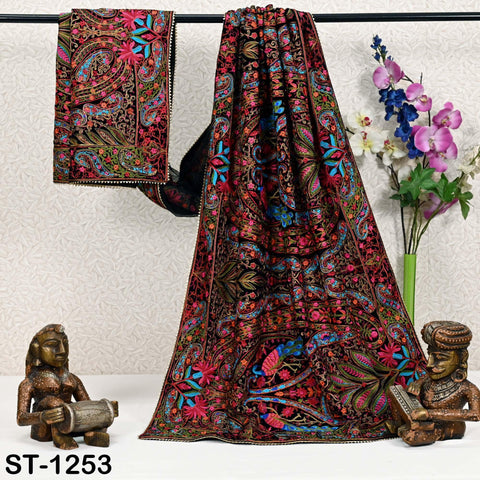 a vibrant, intricately patterned shawl hanging on a rack, accompanied by two small statues and a vase of flowers.