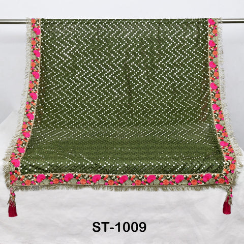 a green and pink decorative fabric with a floral pattern, hanging on a white surface.