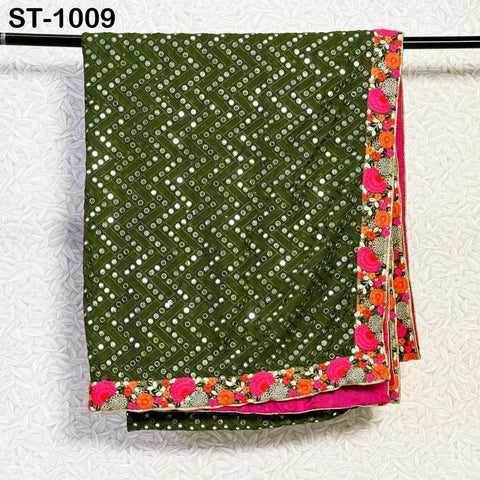 a green and pink patterned fabric with a floral border, hanging on a black rod.